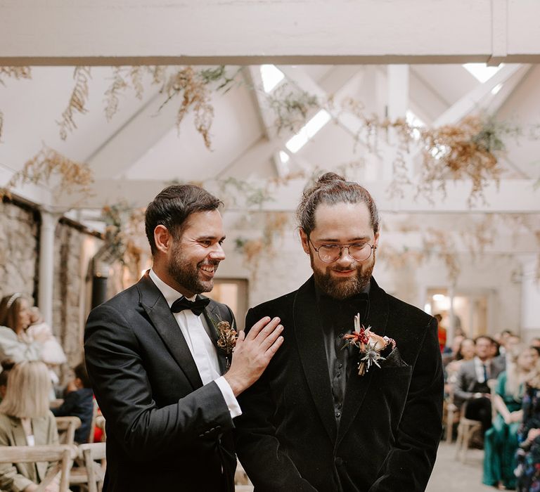 Groomsman in black tie comforts the groom just before the wedding ceremony begins