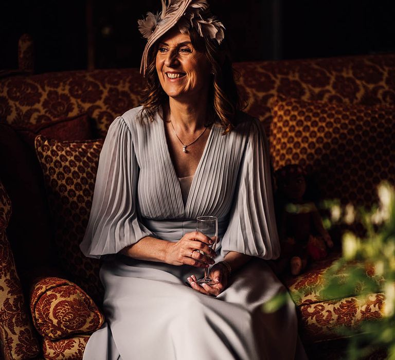 Wedding guest in pleated light blue dress with intricate pink feather hat