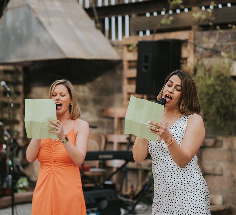 Two wedding guests perform a funny wedding reading at the glass house wedding venue 