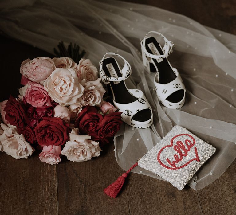 Light pink and red rose wedding bouquet with pearl bridal clutch and black and white Chanel wedding shoes 