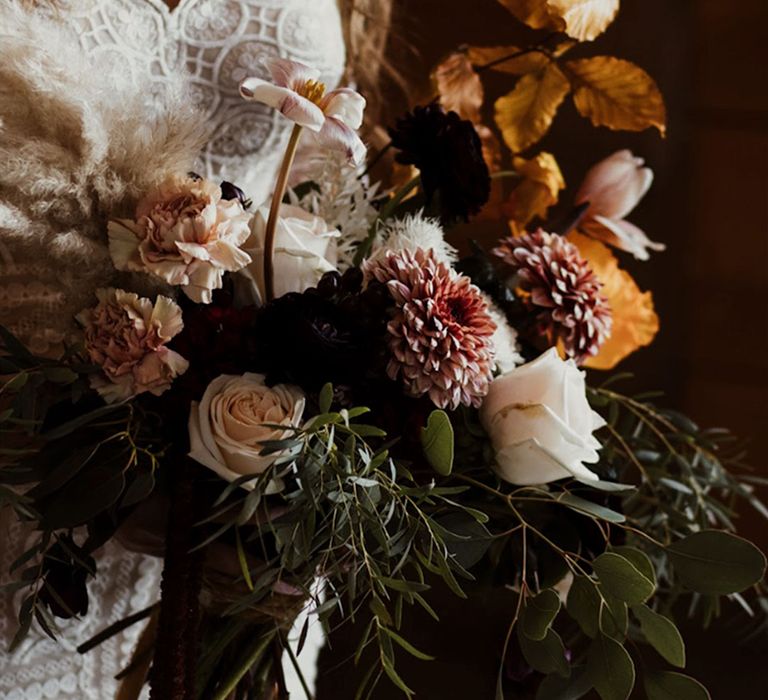 Pastel wedding flowers in a bouquet with autumnal leaves decorating the bouquet 