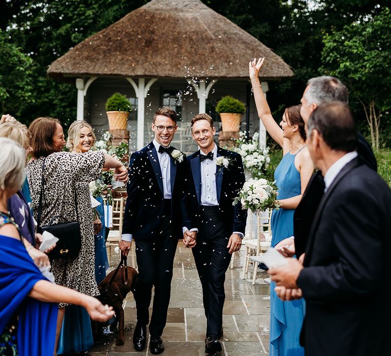 Confetti moment for the two grooms at their outdoor wedding ceremony 