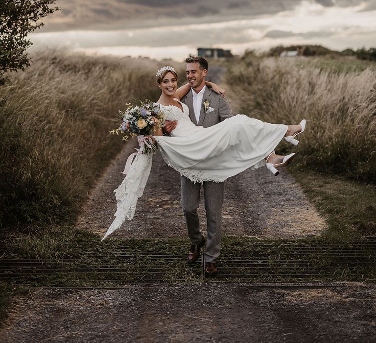 Bride wearing Justin Alexander wedding dress being picked up by the groom for cute couple photo 