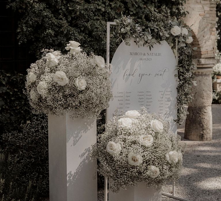 White roses and white gypsophila with white wedding table plan signage 