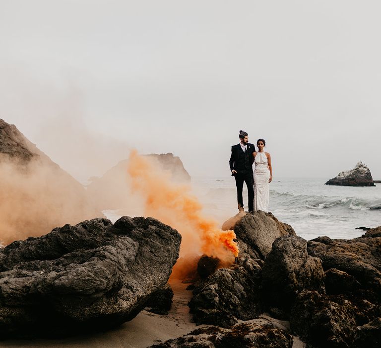 Orange smoke bomb portrait at coastal elopement 