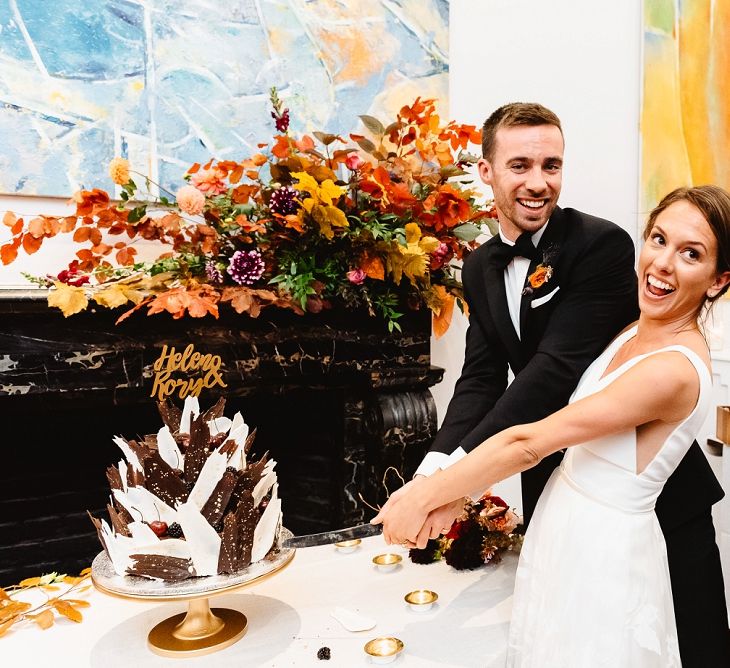 Bride and groom cutting the wedding cake at Autumn black tie wedding