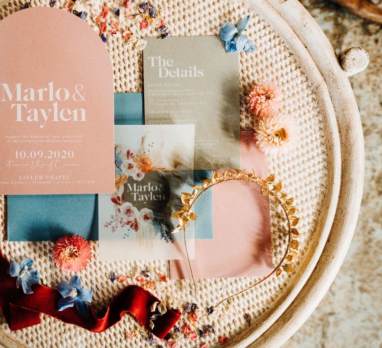 Pink and blue wedding stationery resting on a wicker table 