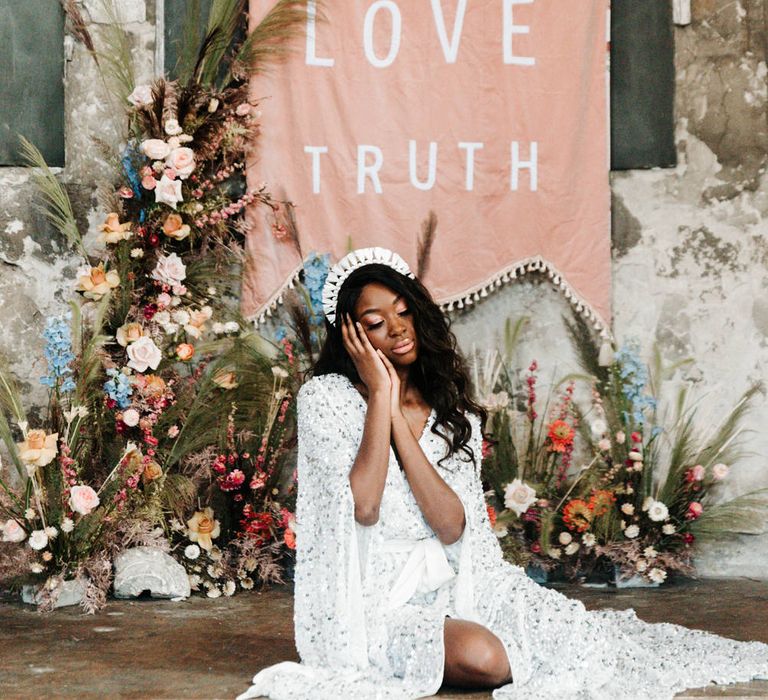 Black bride in silver sequin wedding dress and headband sitting at the altar