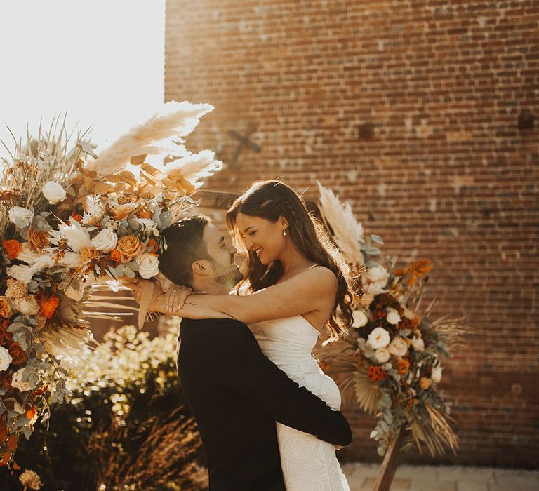 Groom lifts bride into the air for a kiss