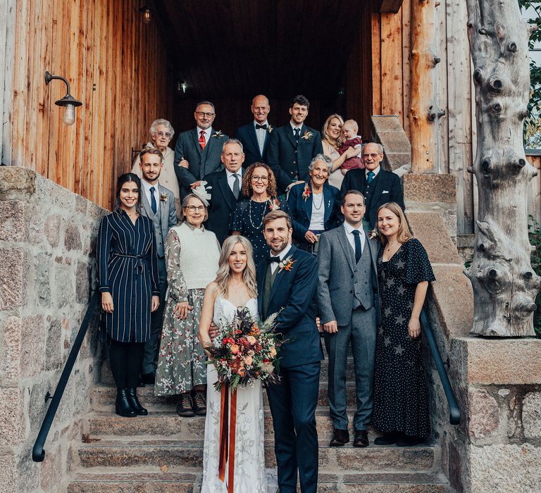 Bride & groom stand on steps with wedding party after intimate ceremony