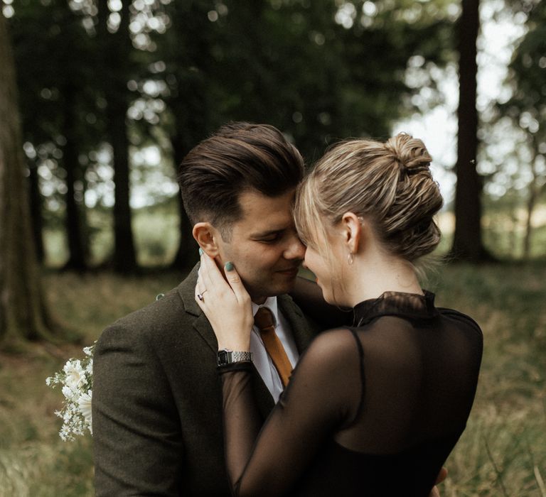 Bride & groom embrace with bride wearing mesh black top wedding dress