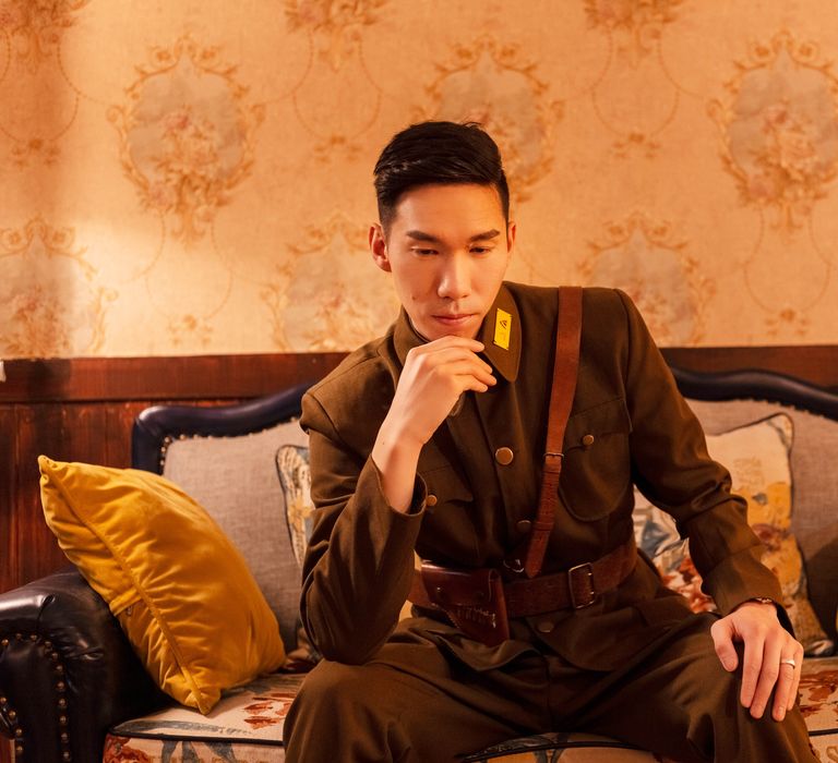 Groom-to-be leans head on hand in traditional military attire