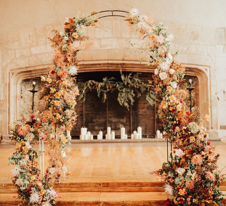 Aisle and altar autumn themed wedding decor with pillar candles, and orange wedding flower arch