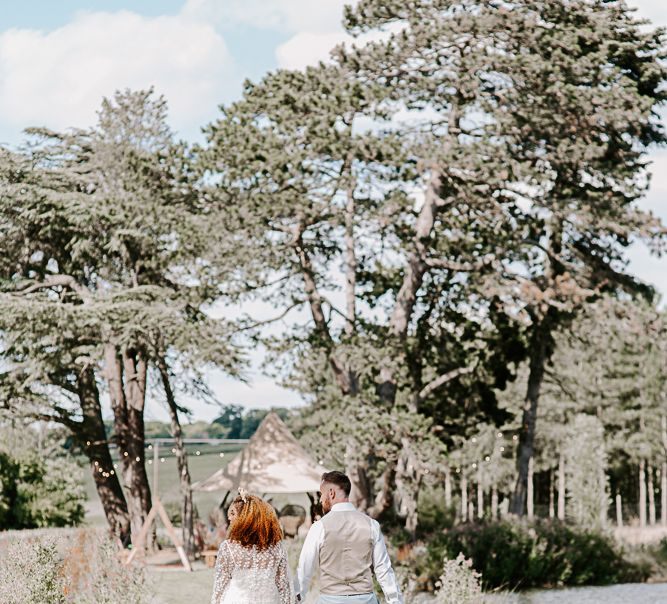 Bride & groom walk outdoors with their backs to the camera on wedding day