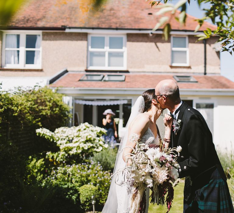 Father of the bride kisses her cheek on the morning of the wedding