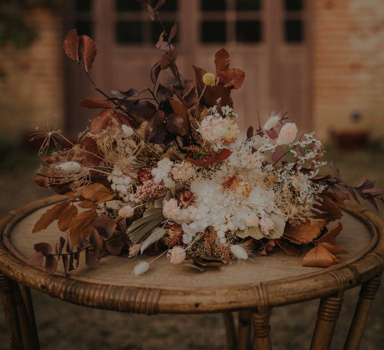 Autumn wedding bouquet with brown leaves, white flowers and foliage 