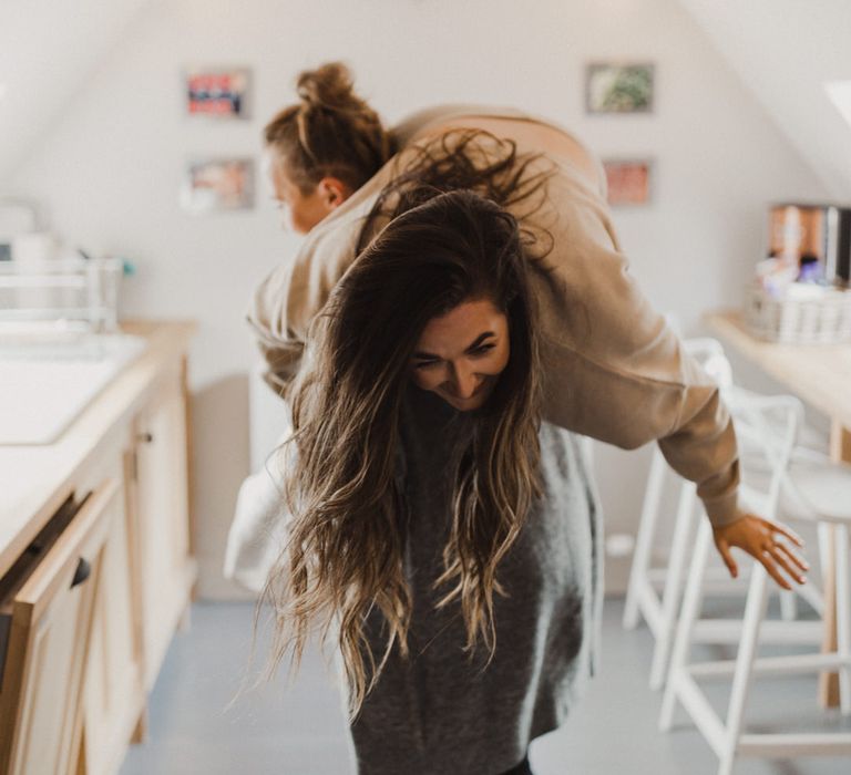 Lorna being carried through the kitchen over Tasha's shoulder