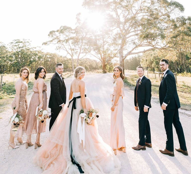 Bride and groom with blush bridesmaids and groomsmen in tuxedos