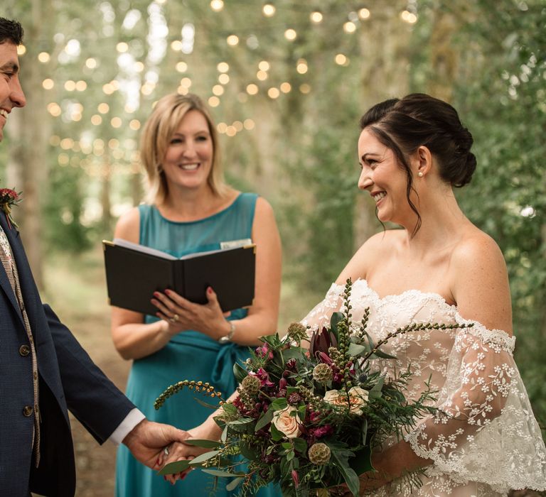 Bride & groom during vow renewal with fairy lights in the background