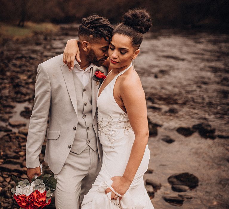 Bride & groom stand outside whilst groom wears grey suit