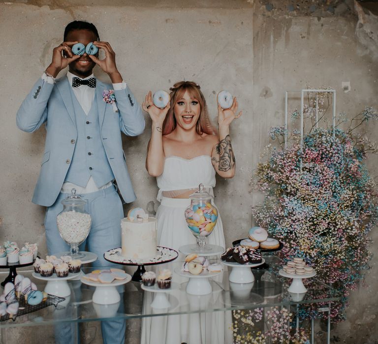 Dessert table with spray painted gypsophila flower clouds, drip wedding cake, doughnuts, flying saucers, cupcakes and macaroons