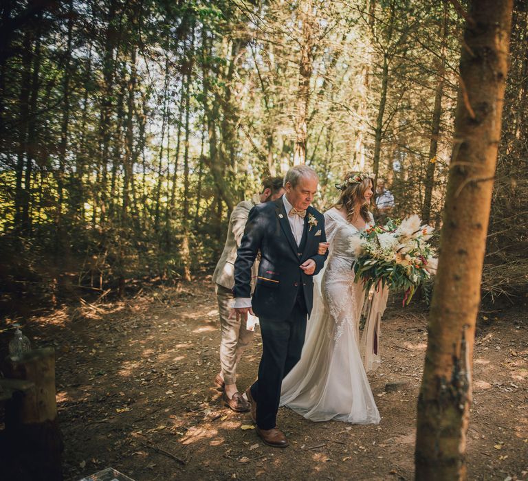 Bride walks through the woodlands holding floral bouquet