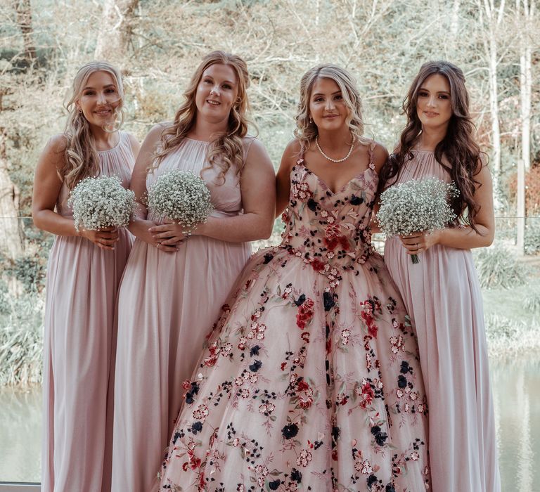 Bride stands with bridesmaids wearing blush pink bridesmaids dresses