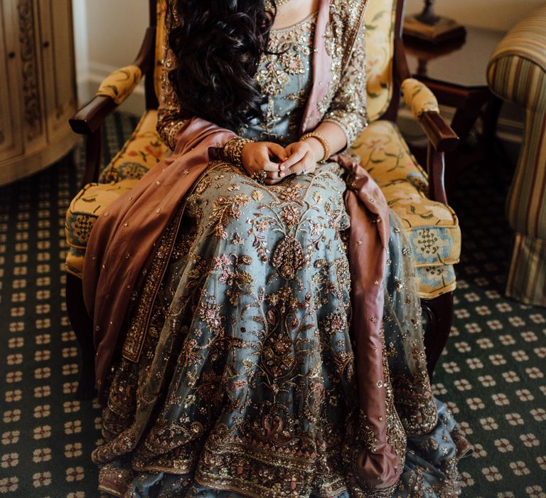 Bride sits on chair as she wears traditional saree and her dark hair in loose curls