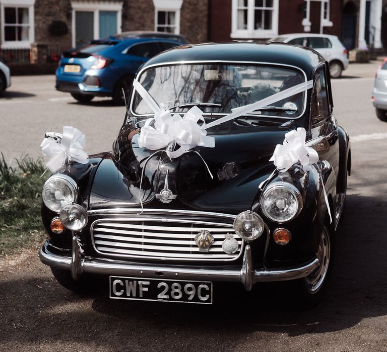 Black vintage Morris Minor with white wedding ribbon