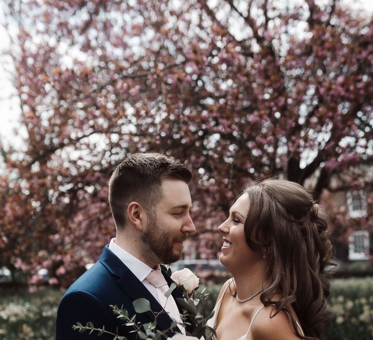 Bride and groom hug at their church wedding ceremony, the bride is holding a large bouquet of white and pink roses