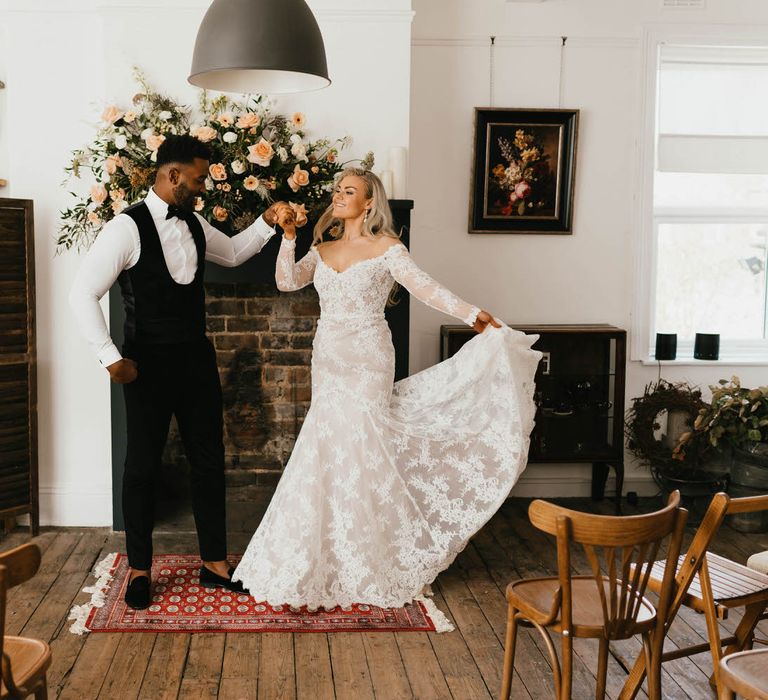 Groom twirling the bride at the altar of micro wedding ceremony, the bride is fanning out the skirt off her shoulder lace wedding dress