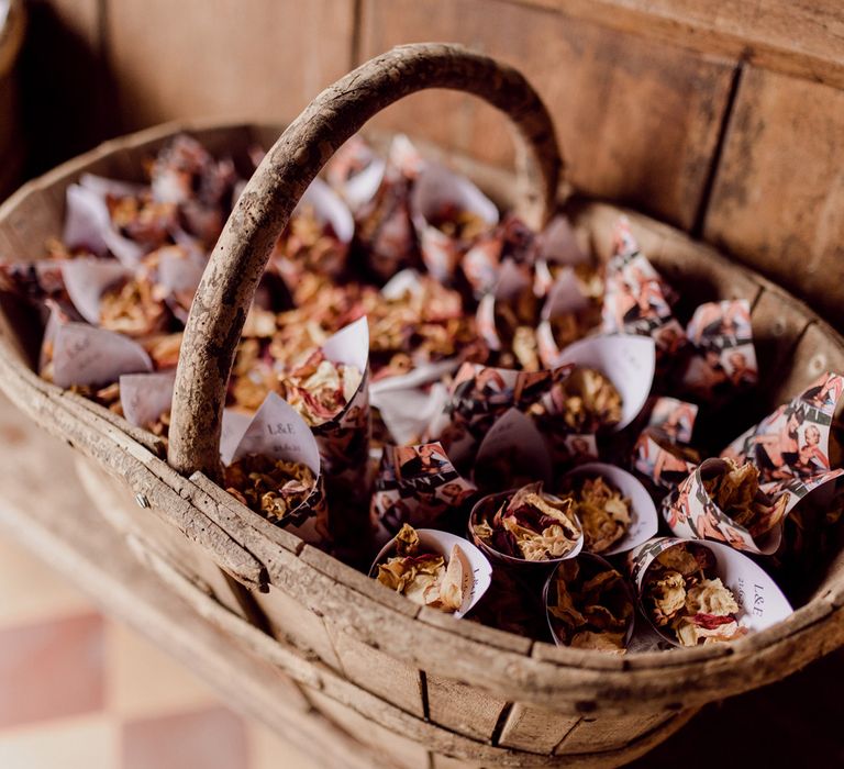 Wooden basket all of dried confetti cones on church pew before home farm wedding