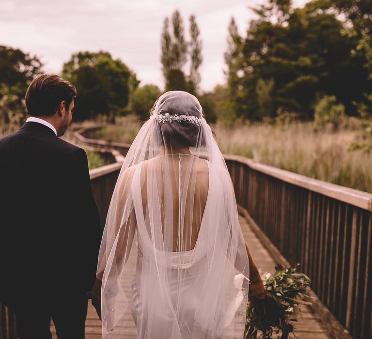 Bride in a cowl back satin wedding dress and Juliet wedding veil with lace cap detail 