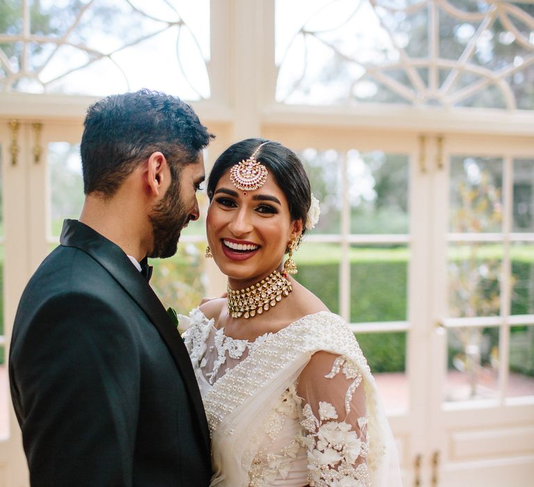 Bride & groom laugh together as bride wears white traditional saree 