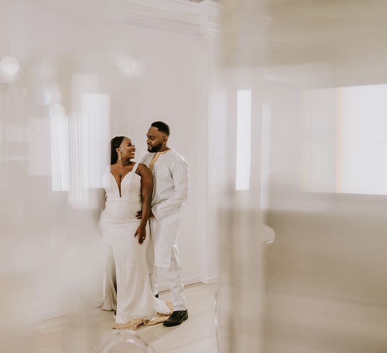 Groom wraps his arms around bride as they wear reception outfits at the Core Clapton