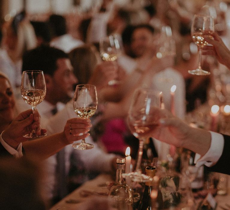 Wedding guests raise their glasses of white wine during wedding breakfast at Loseley Park 