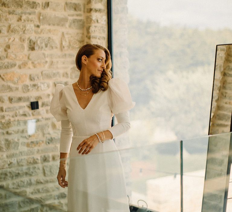 Bride looks over her shoulder out the window on her wedding day