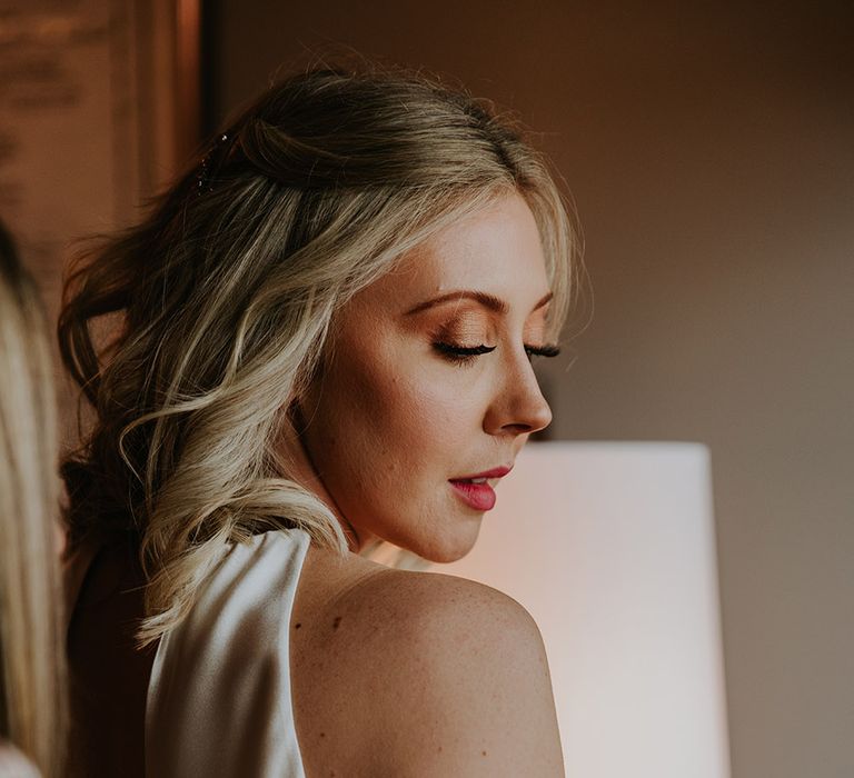 Bride in a champagne coloured wedding dress with light brown eyeshadow and long lashes and light pink lipstick 