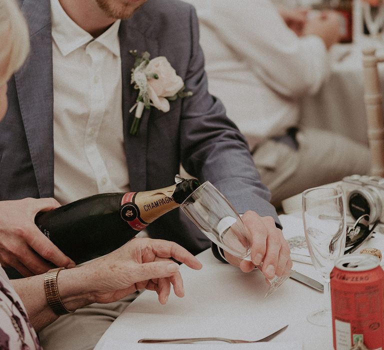 wedding guest pouring champagne at the back garden marquee wedding reception 