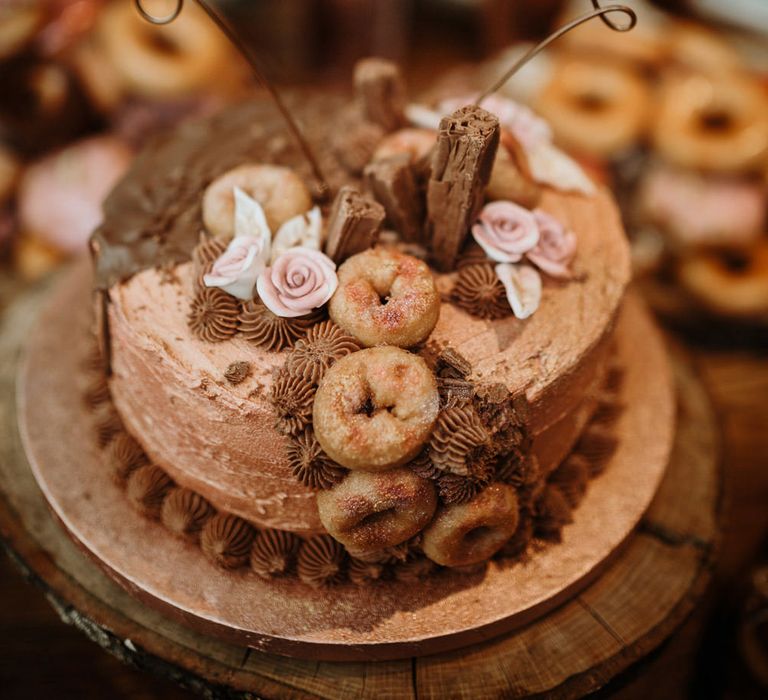 single tier wedding cake laden with macaroons and miniature doughnuts and a bronze 'lobsters' wedding cake topper 