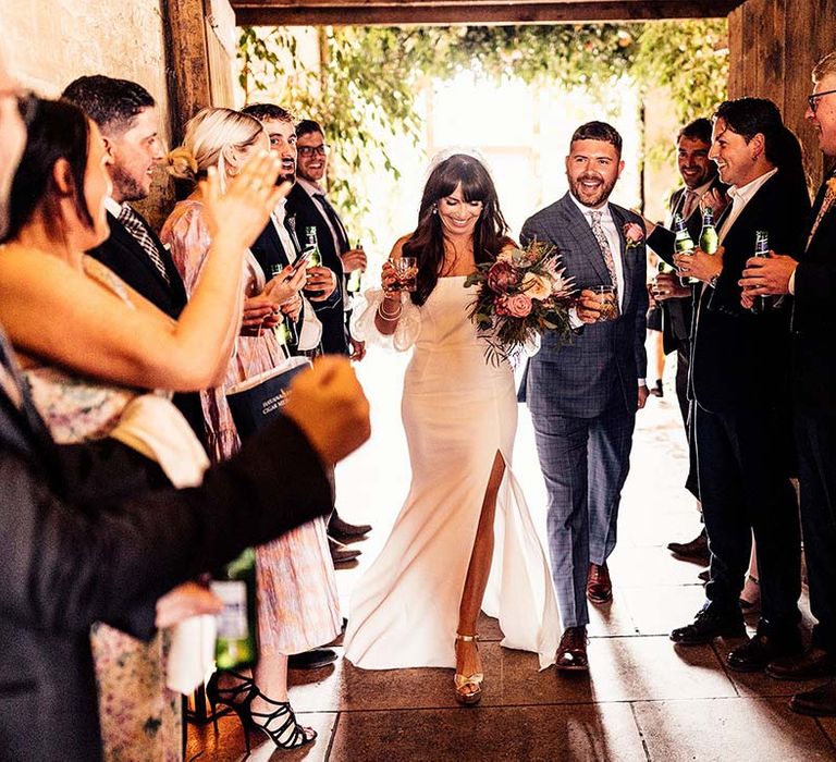 Groom in a check blue suit and bride in a strapless wedding dress with detachable sleeve and front split 