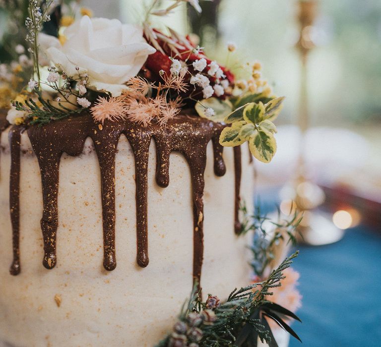 White frosted cake with chocolate drip and floral decor