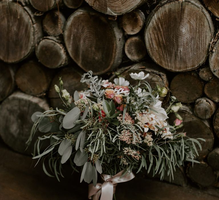 Floral bouquet complete with green foliage and tied with ribbon