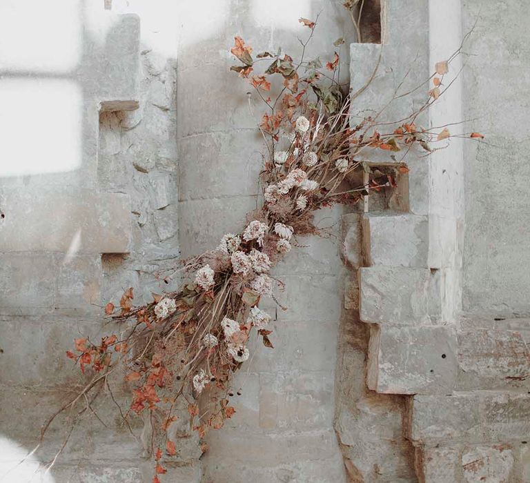 Minimalist wedding flower arrangement with twigs, vines, foliage and dried flowers 