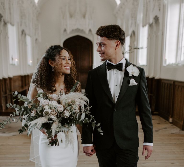 Bride & groom walk together and look lovingly at one another on their wedding day