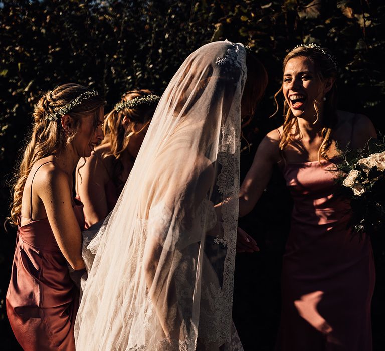 Bride walks with her bridesmaid who wear pink dresses