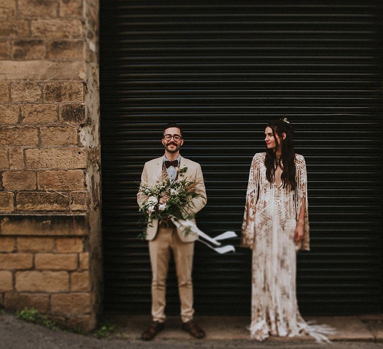 Bride & groom stand in front of black door and brick wall on their wedding day