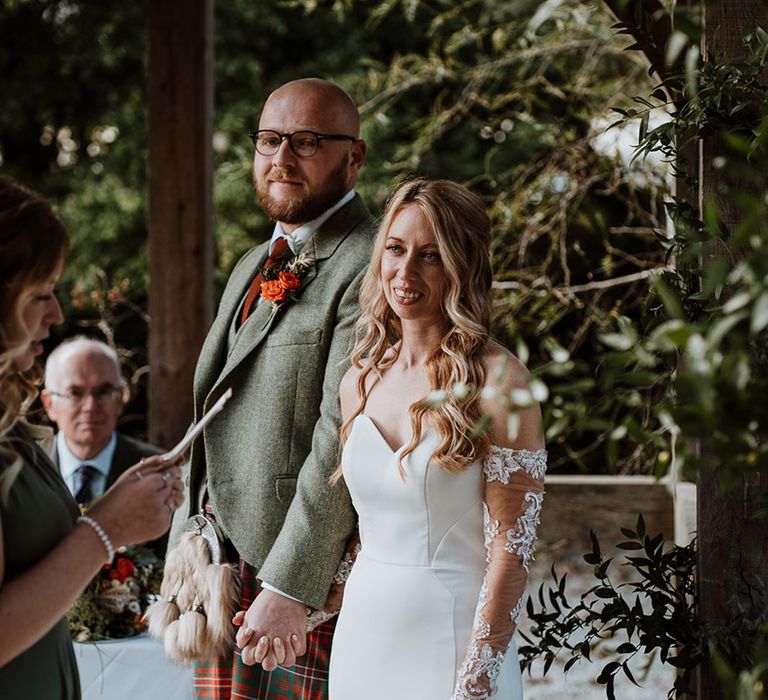 Bride & groom hold hands outdoors for Autumnal wedding day