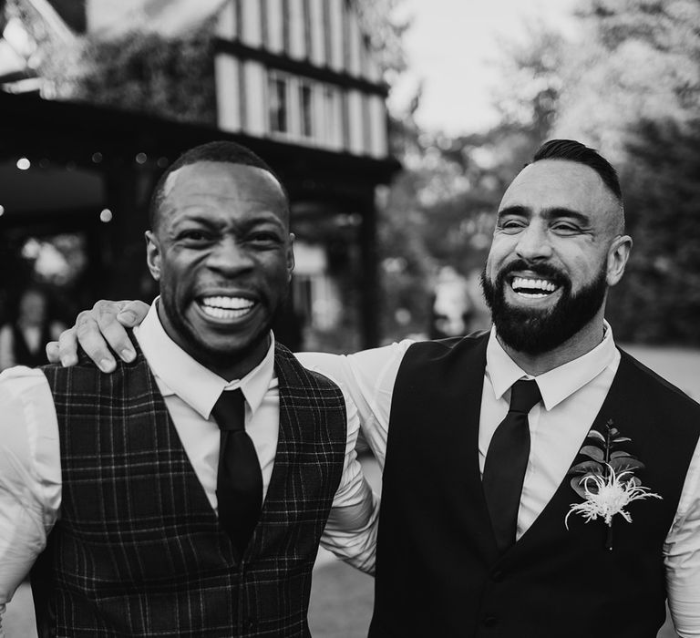 Groom stands with groomsmen as they laugh with one another