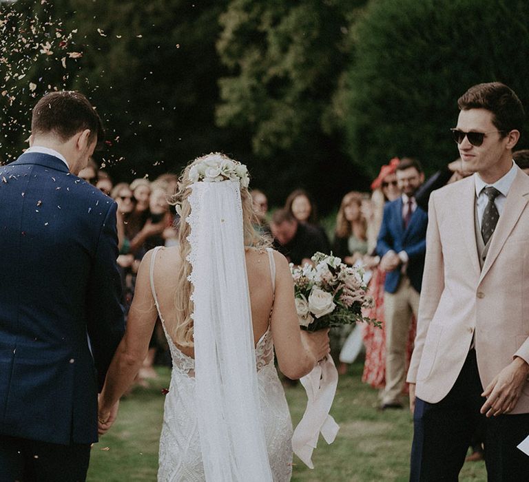 Bride in lace wedding dress and matching lace veil with flowers in her hair and pink and white wedding bouquet